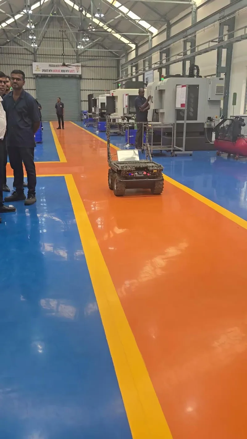 The Versor robot on the painted floor of a large workshop, with people watching